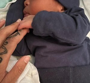Ein Baby hält mit seiner Hand einen Finger seiner Mutter